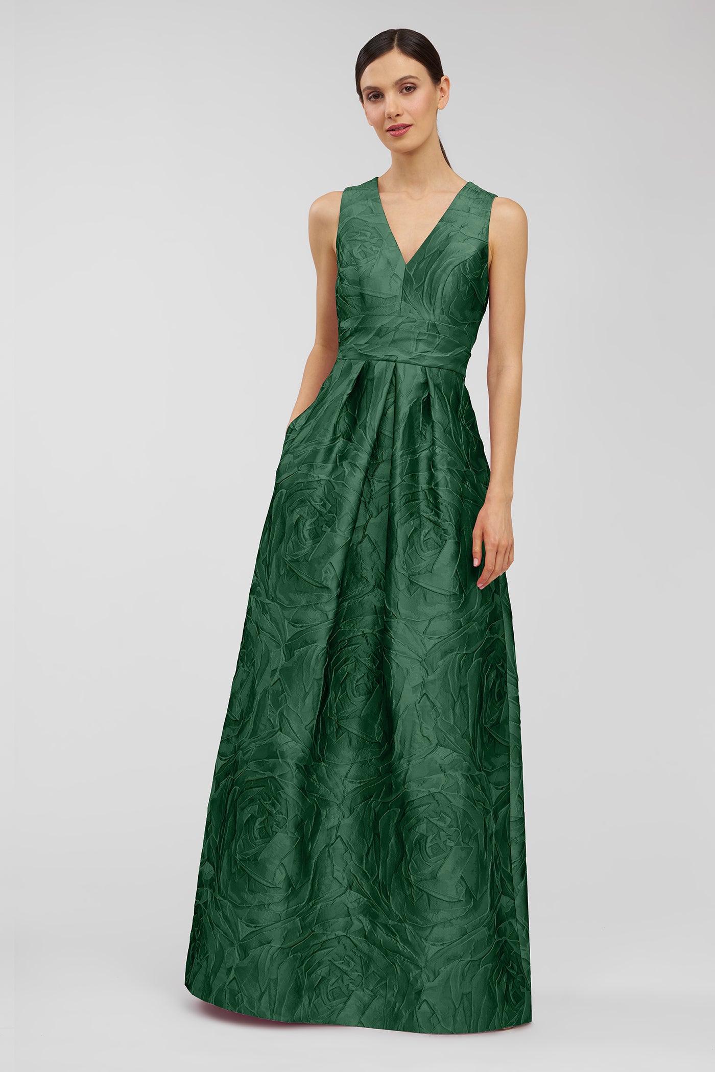 Woman wearing a green evening gown on a light gray background