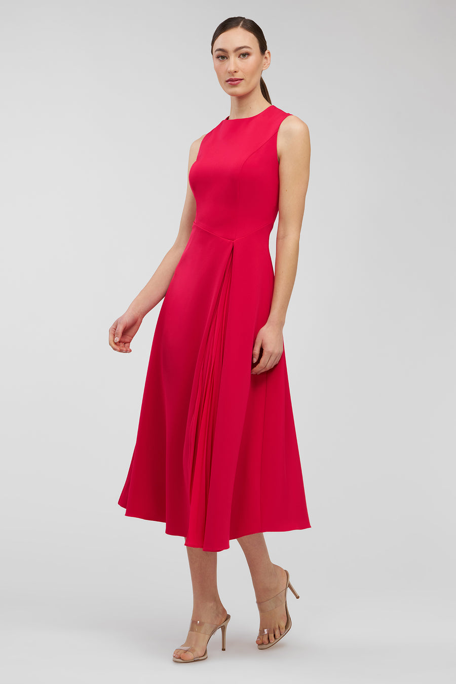 Woman wearing a bright pink sleeveless dress on a light gray background