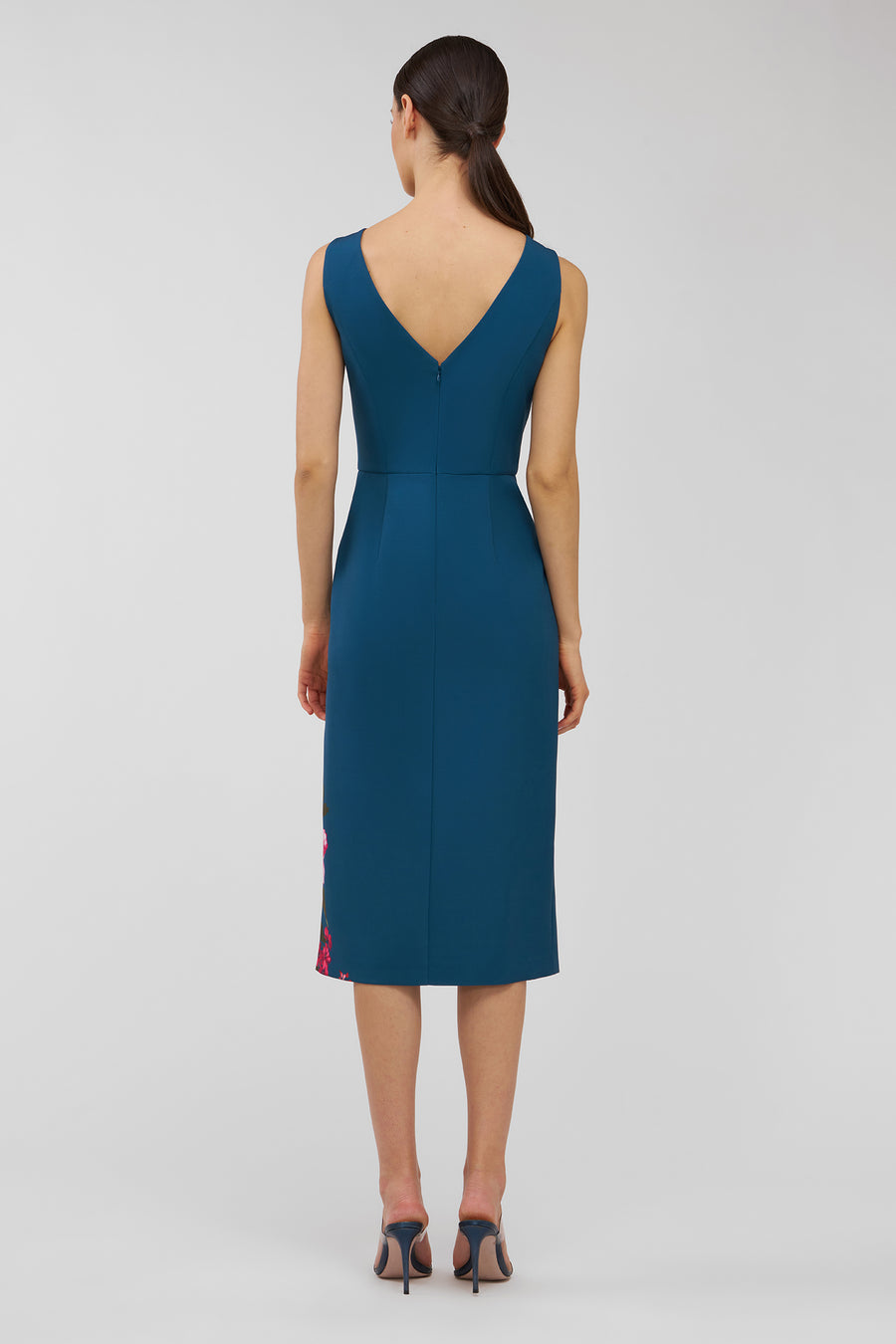 Woman wearing a teal dress with a V-neckline on a white background