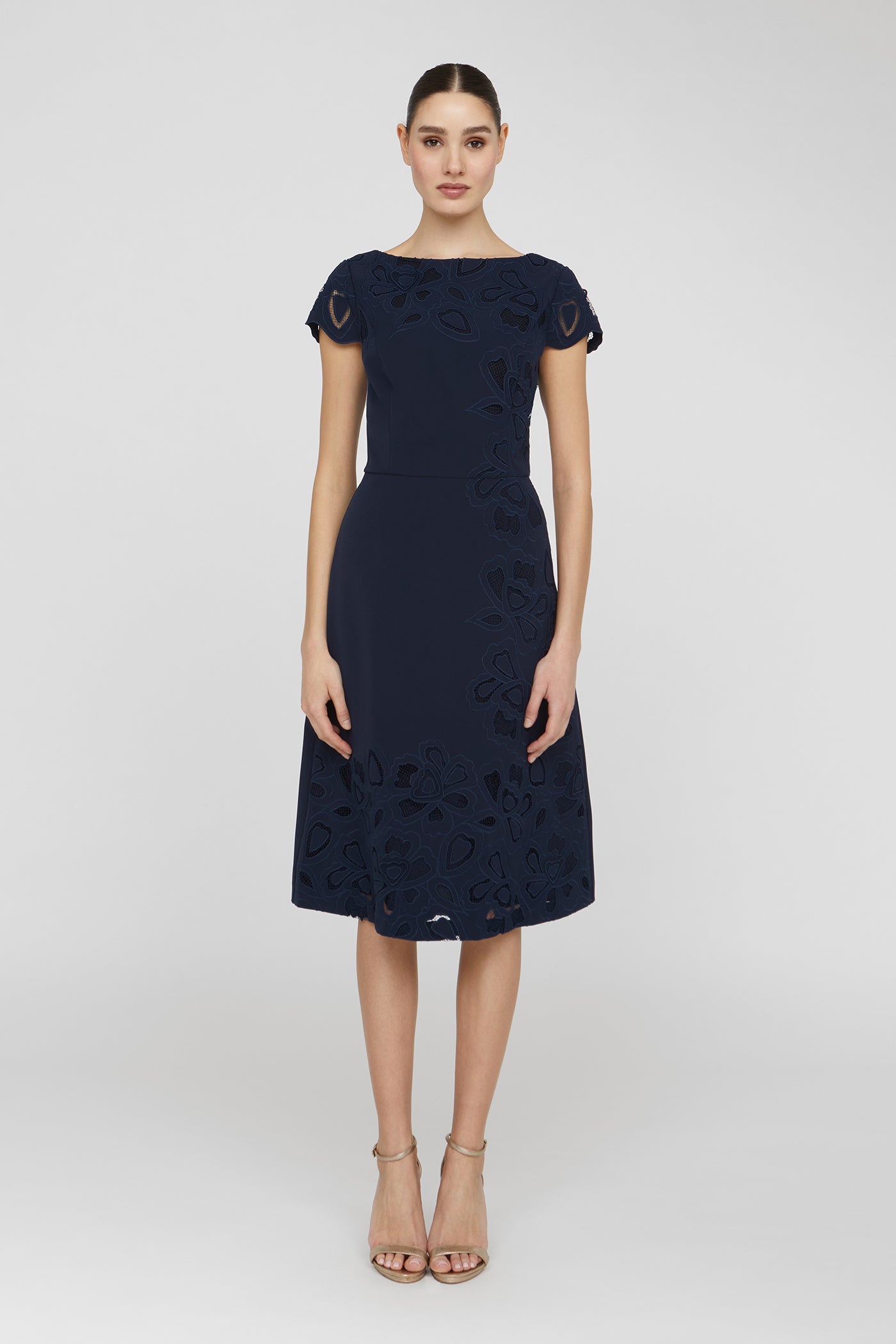 Woman wearing a navy dress with floral patterns on a white background