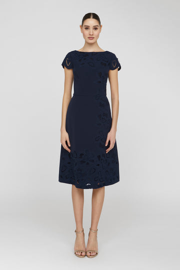 Woman wearing a navy dress with floral patterns on a white background