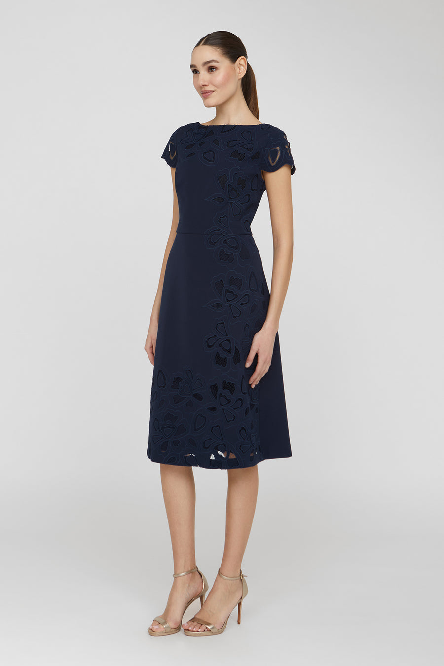 Woman wearing a navy lace dress on a white background