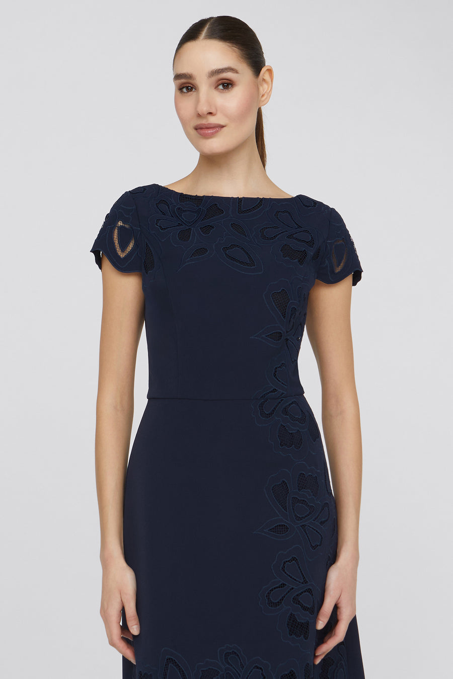 Woman wearing a navy blue dress with lace details on a white background