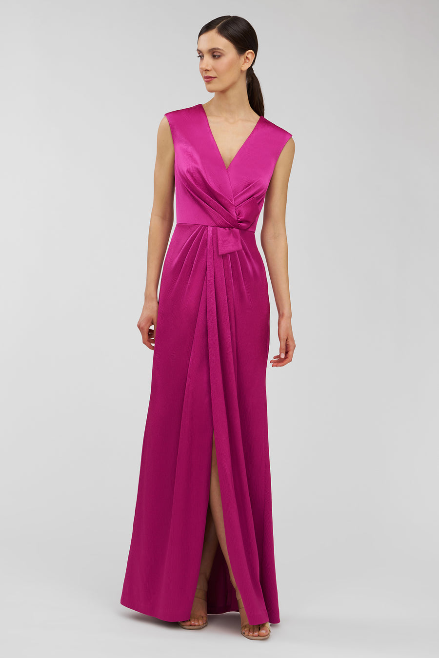 Woman wearing a vibrant pink evening gown on a light gray background