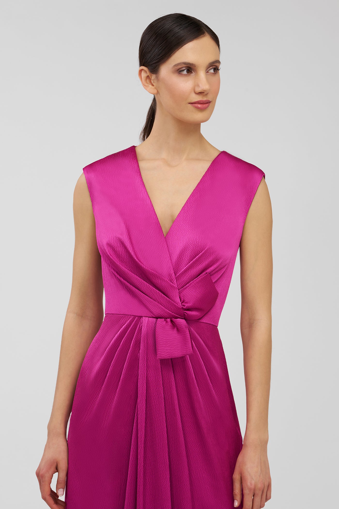 Woman wearing a vibrant pink dress against a plain background