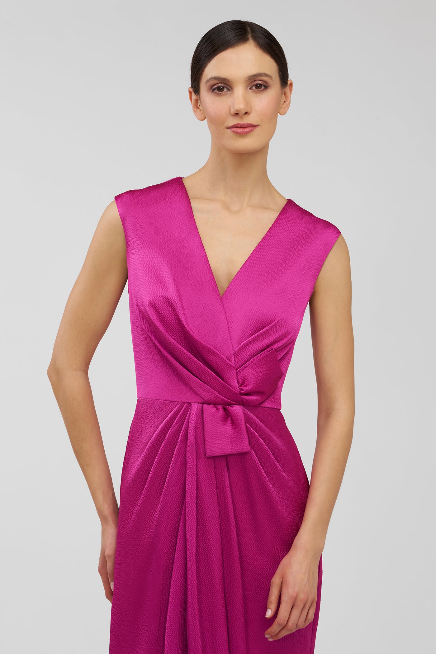 Woman wearing a vibrant pink dress on a plain background