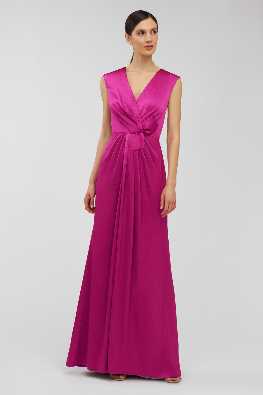 Woman wearing a vibrant pink gown on a plain background