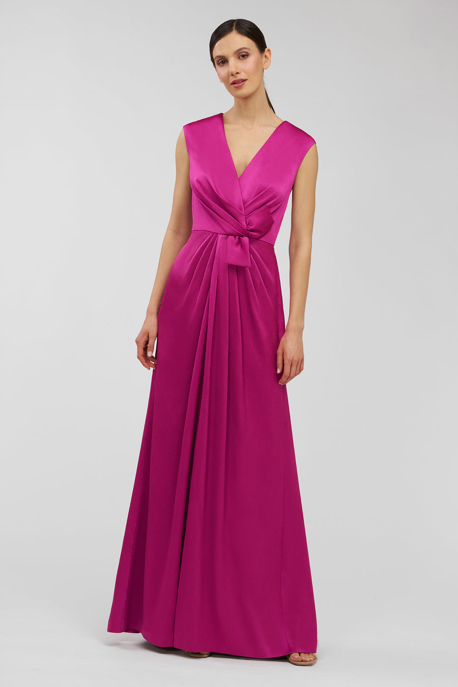 Woman wearing a vibrant pink gown on a light gray background