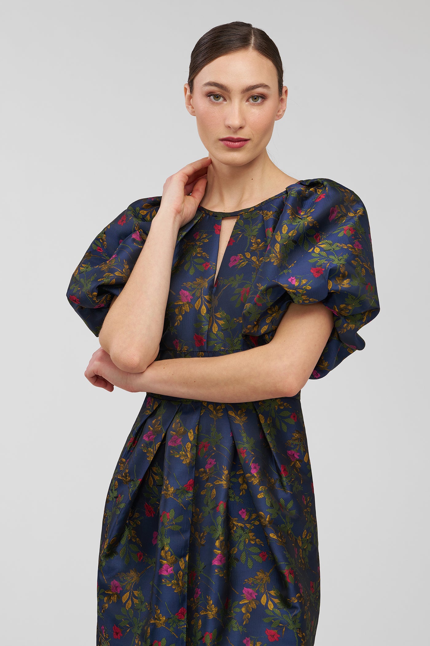 Woman wearing a dark floral dress on a light gray background