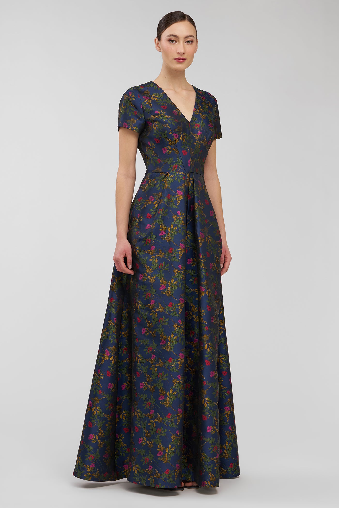 Woman wearing a dark floral patterned dress on a light gray background