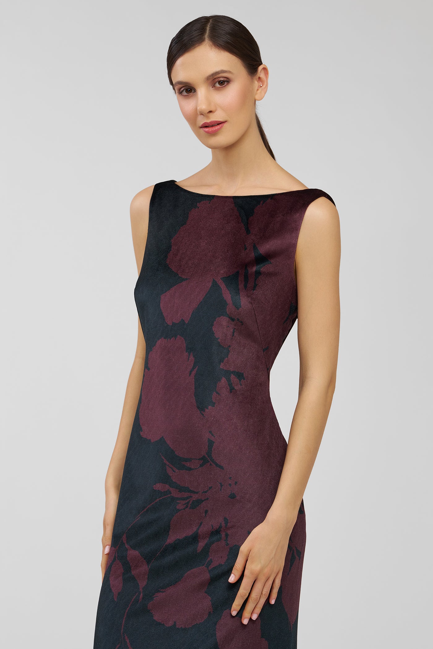 Woman wearing a sleeveless dress with floral pattern on a plain background