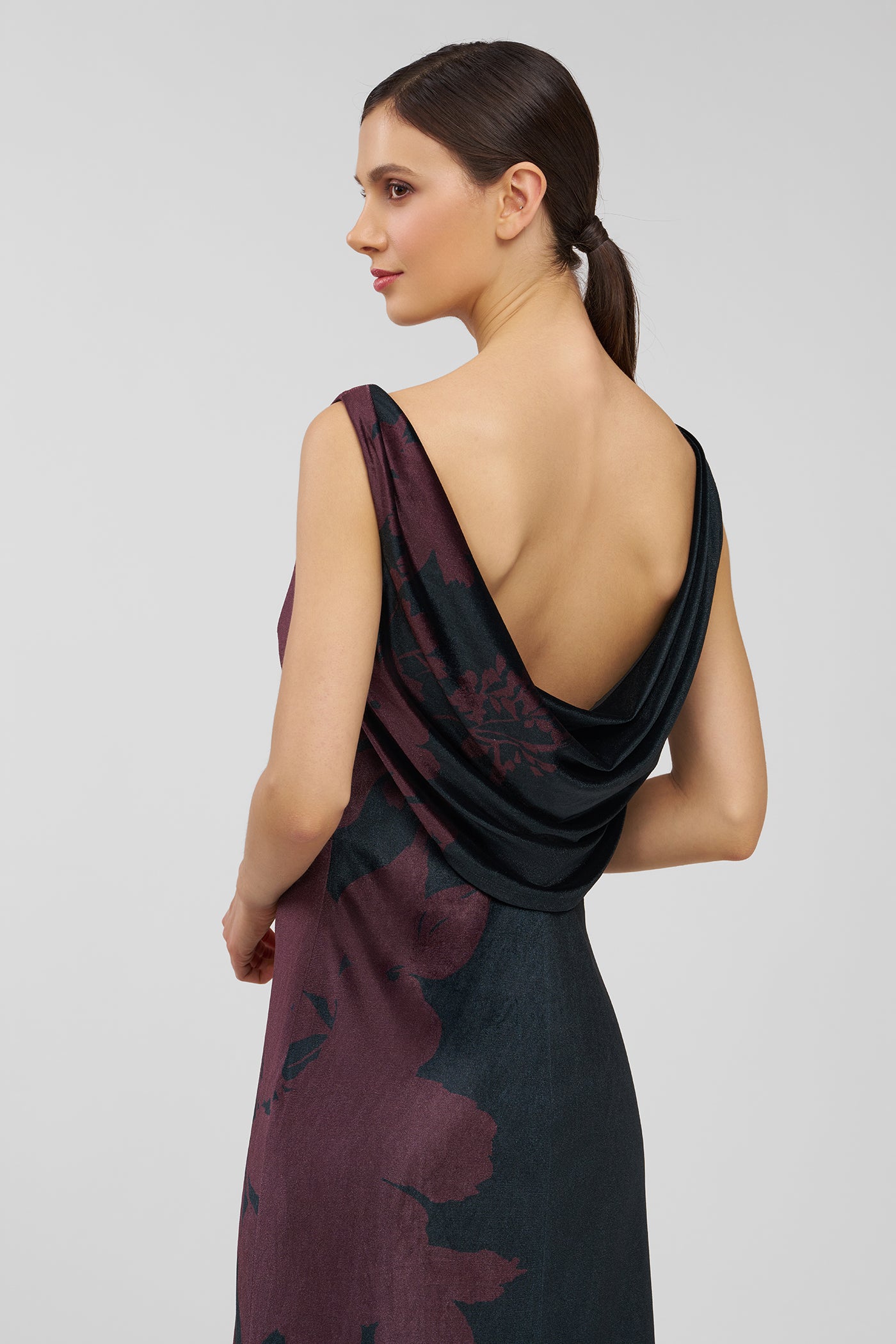 Woman wearing a floral one-shoulder dress on a plain background