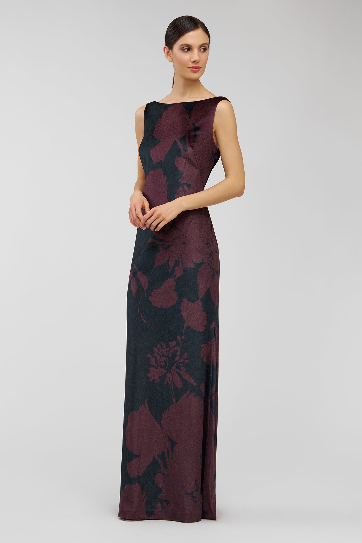 Woman wearing a burgundy and black floral patterned dress on a light gray background