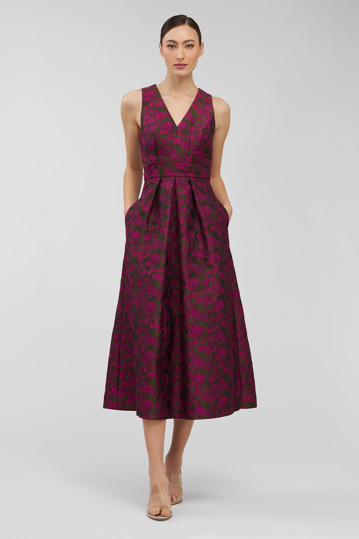 Woman wearing a sleeveless, patterned dress on a plain background