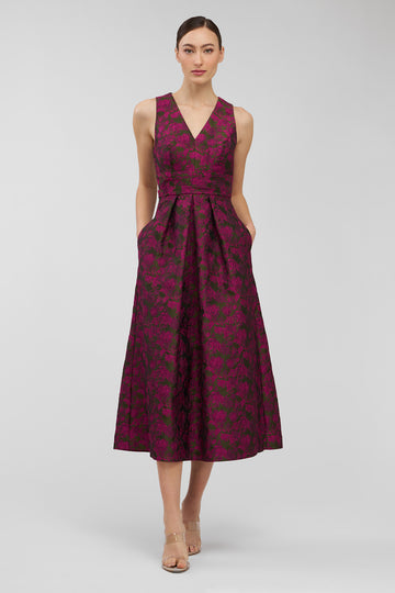 Woman wearing a sleeveless, patterned dress on a plain background