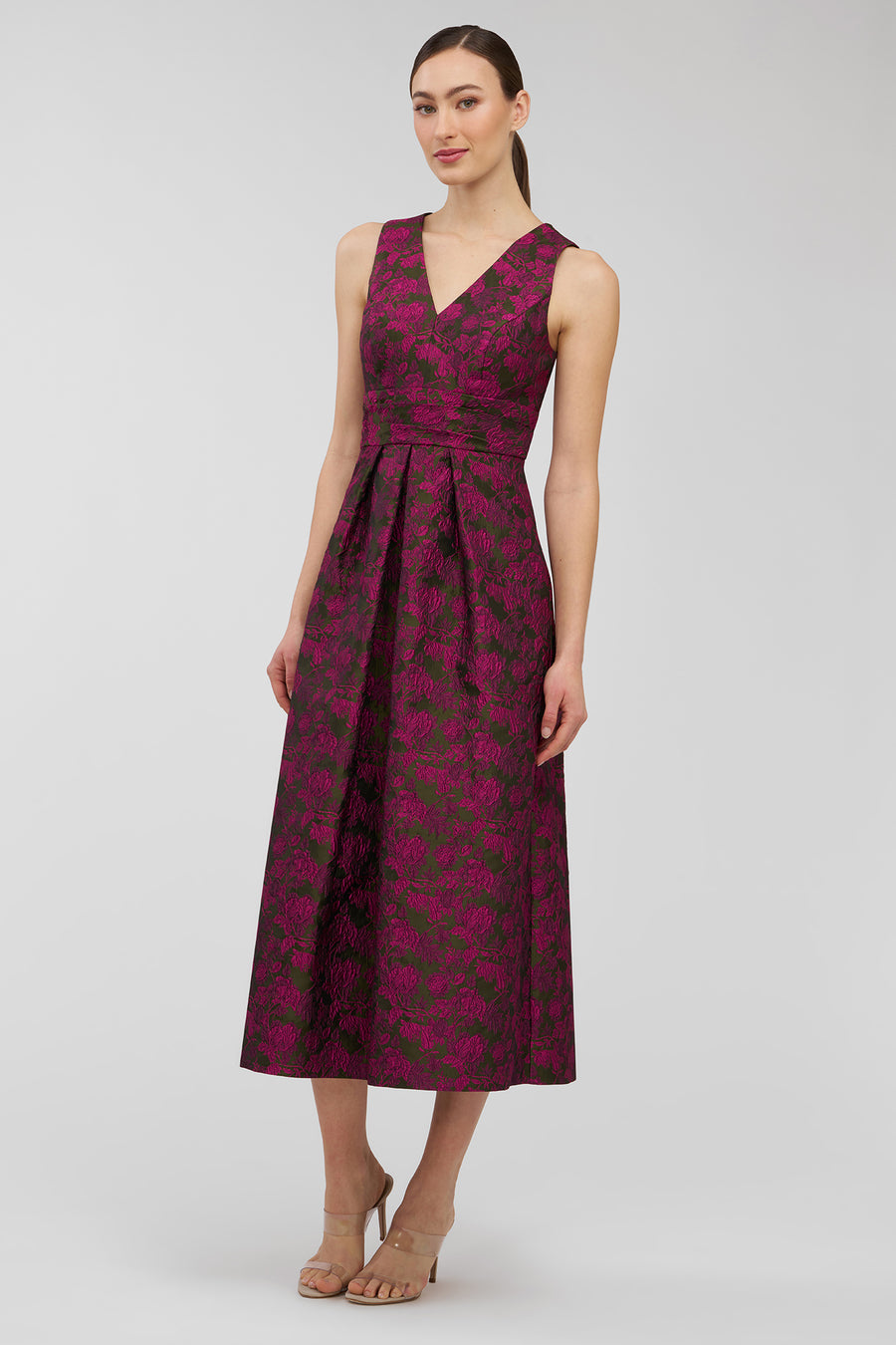 Woman wearing a sleeveless, patterned dress on a plain background