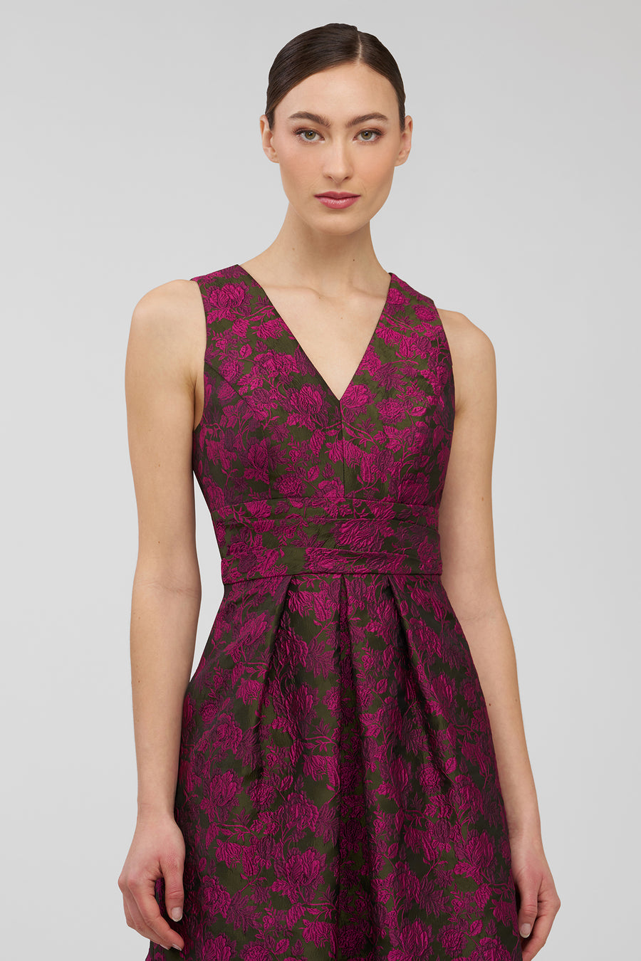 Woman wearing a sleeveless dress with a floral pattern on a plain background