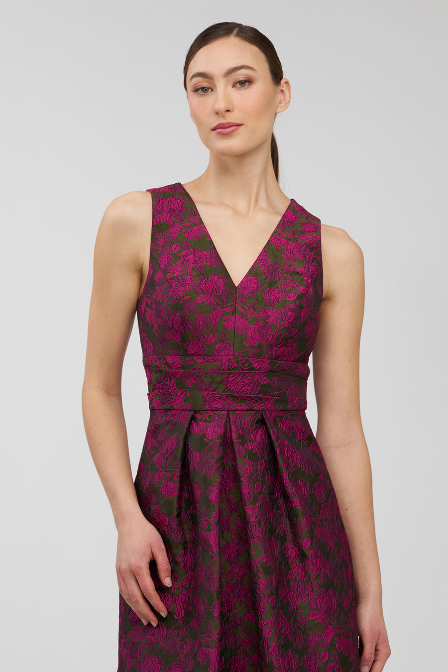 Woman wearing a sleeveless, floral-patterned dress on a plain background