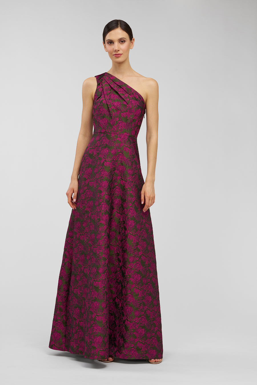 Woman wearing a burgundy one-shoulder dress with floral pattern on a light gray background