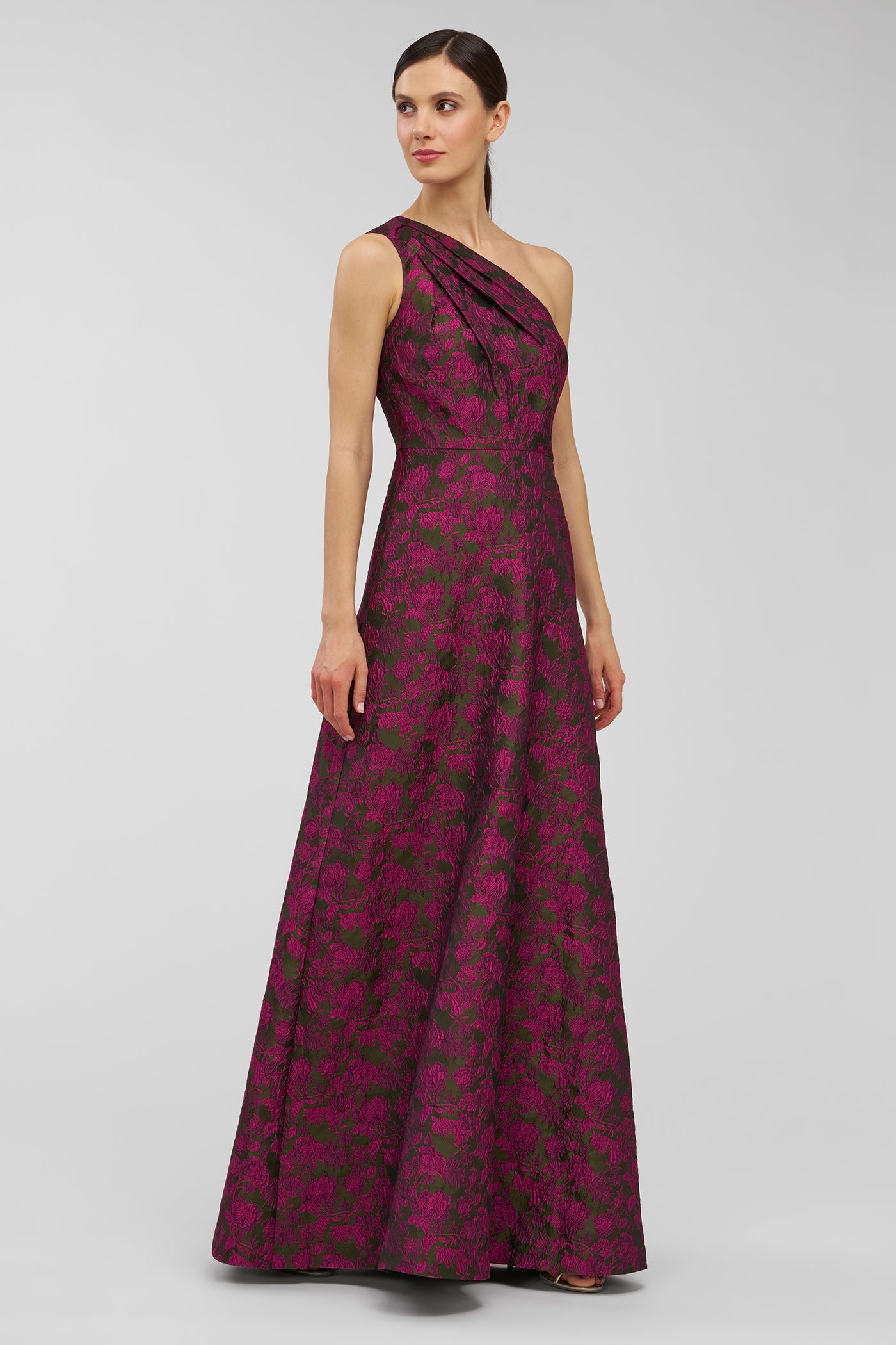 Woman wearing a one-shoulder purple dress with a floral pattern on a gray background