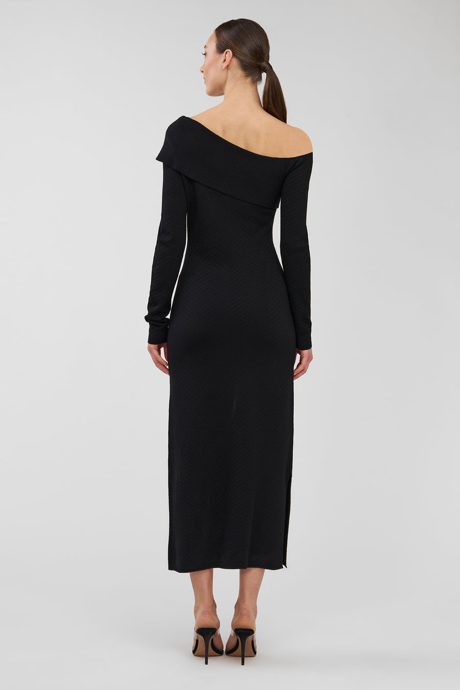 Woman wearing a black off-shoulder dress on a light gray background