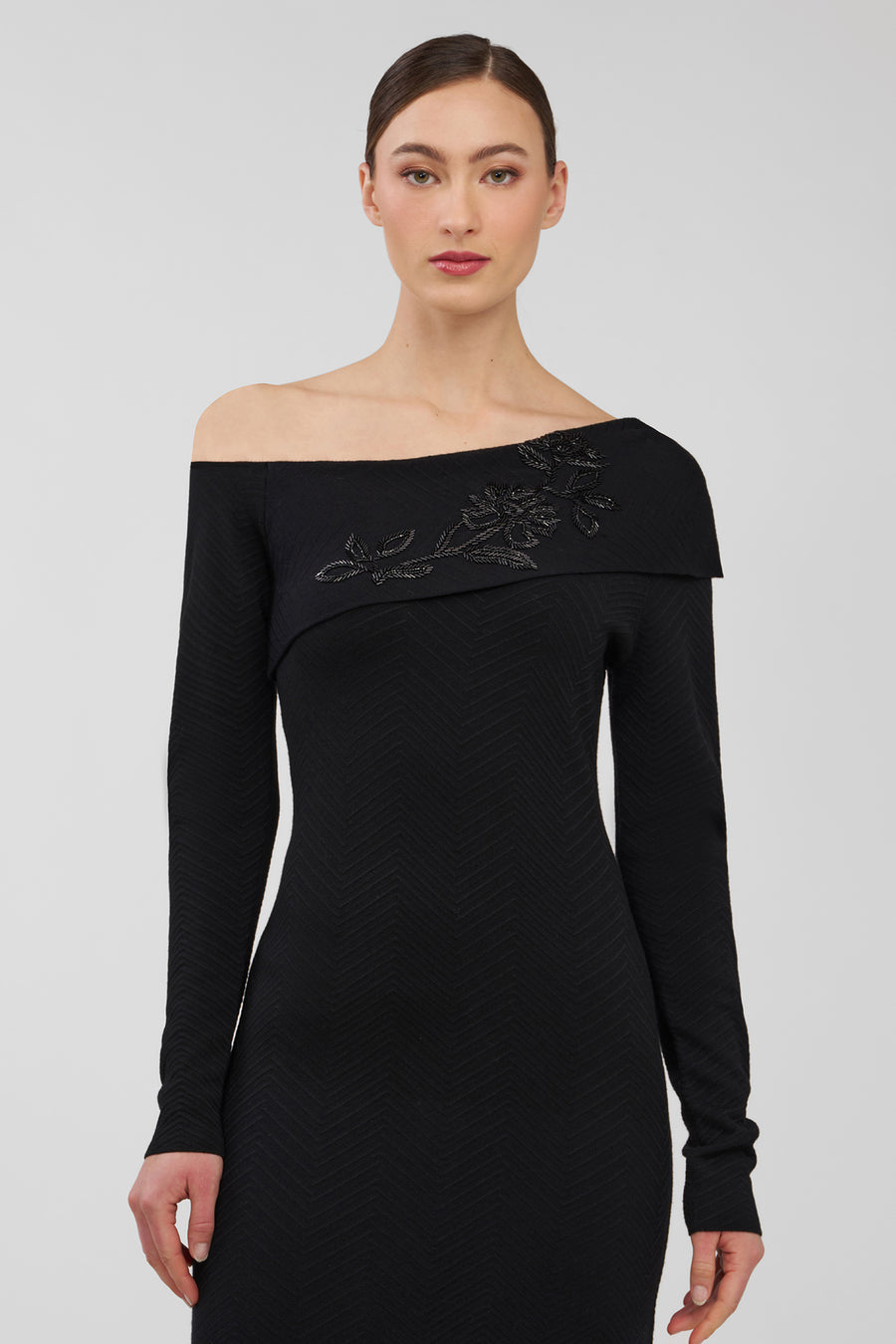 Black off-shoulder dress with floral embroidery on a white background