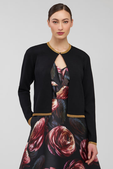 Woman wearing a black cardigan over a floral dress on a light gray background