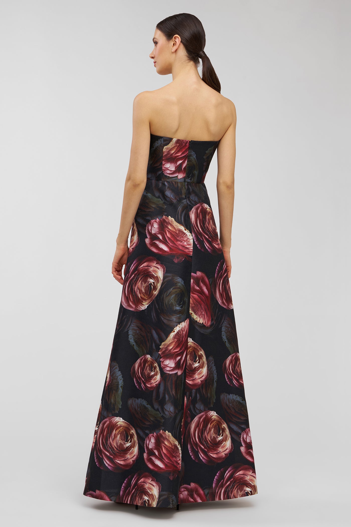 Woman wearing a strapless floral gown with a black background