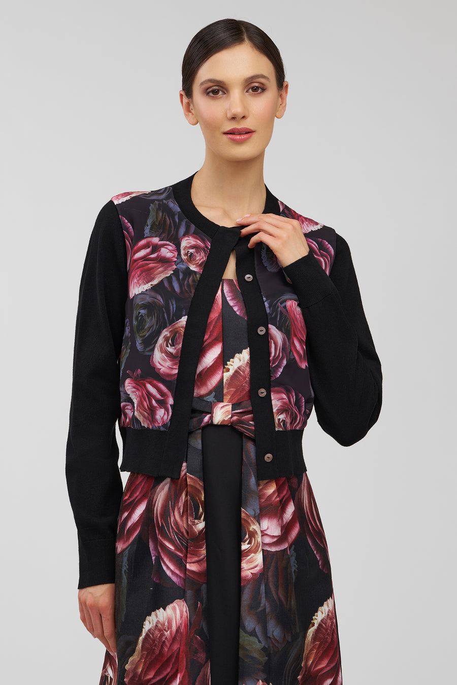 Woman wearing a black outfit with floral patterns on a plain background
