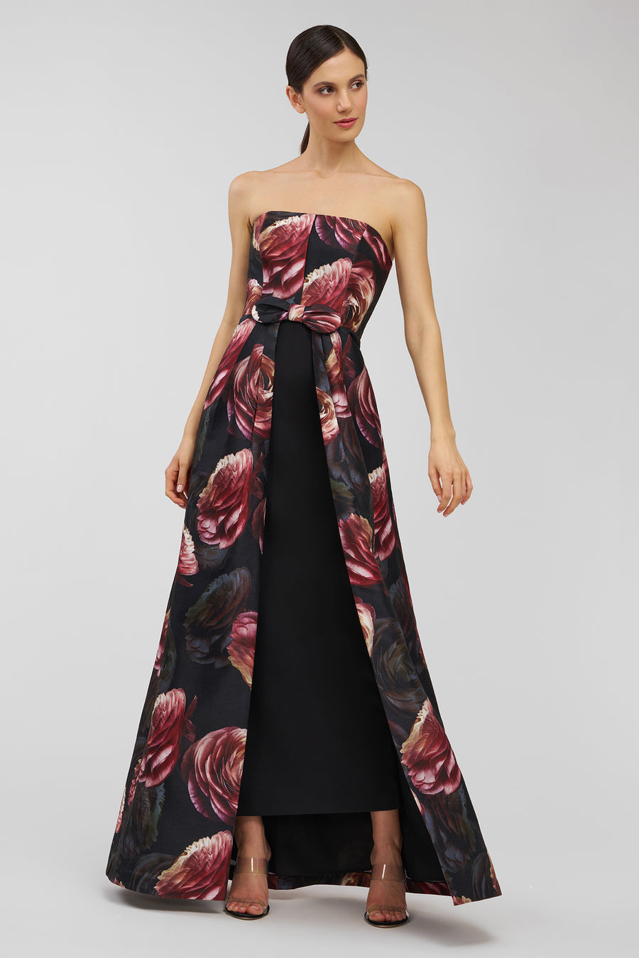 Woman wearing a strapless gown with floral pattern on a plain background