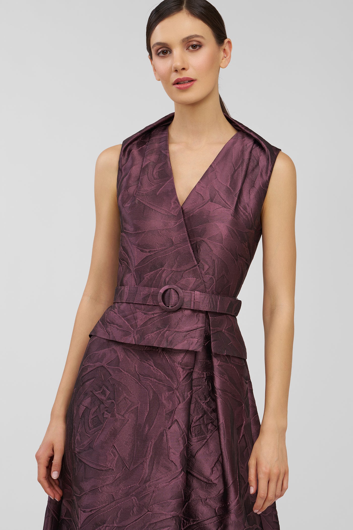 Woman wearing a sleeveless purple dress with a belt on a white background