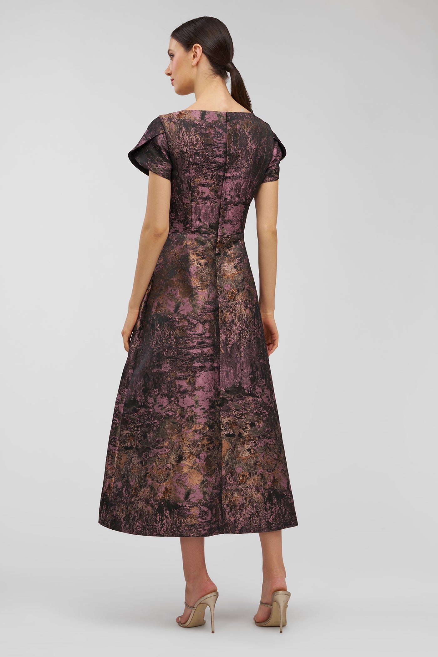 Woman wearing a patterned dress on a plain background