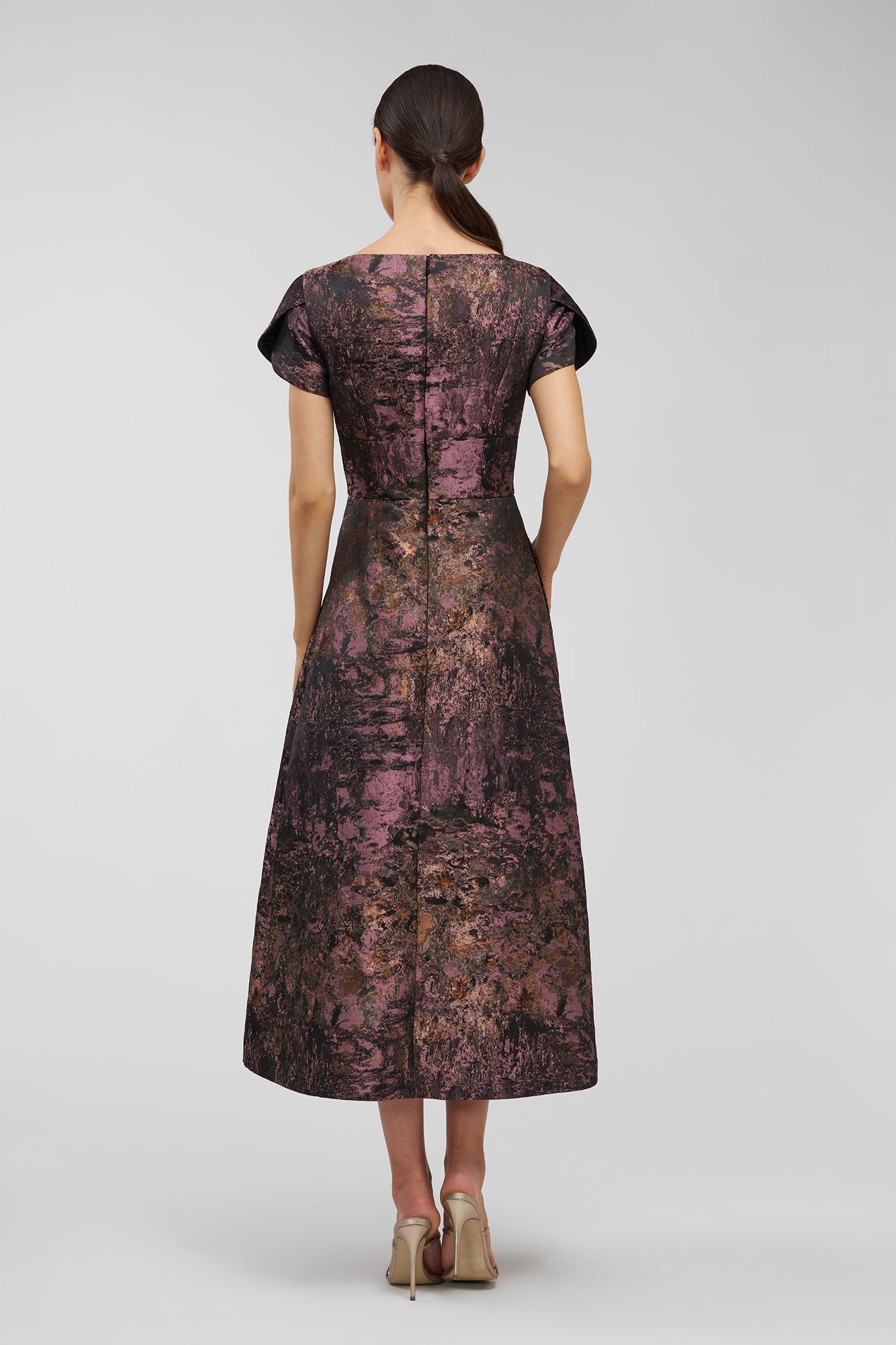 Woman wearing a patterned dress on a plain background