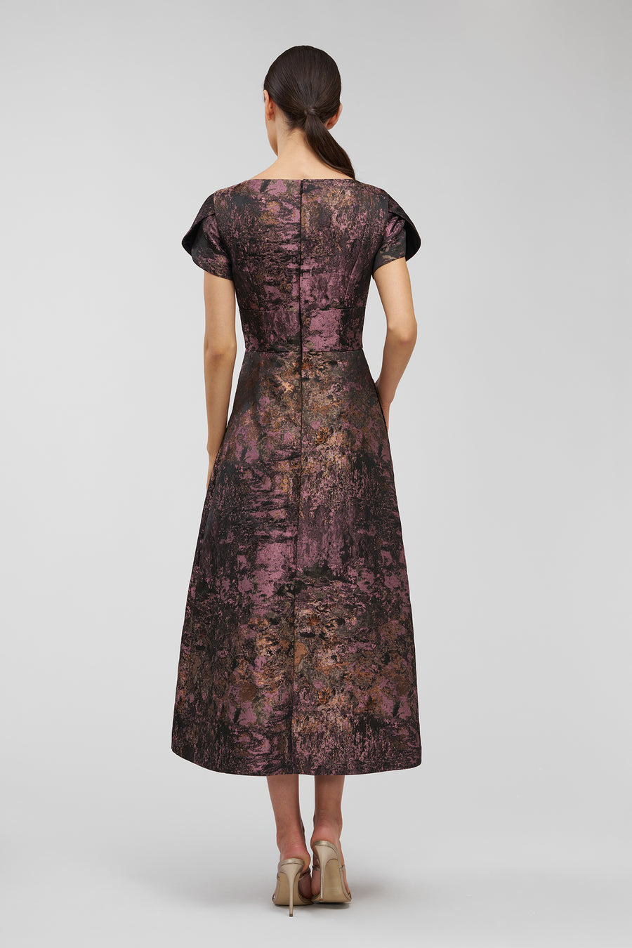 Woman wearing a patterned dress on a plain background