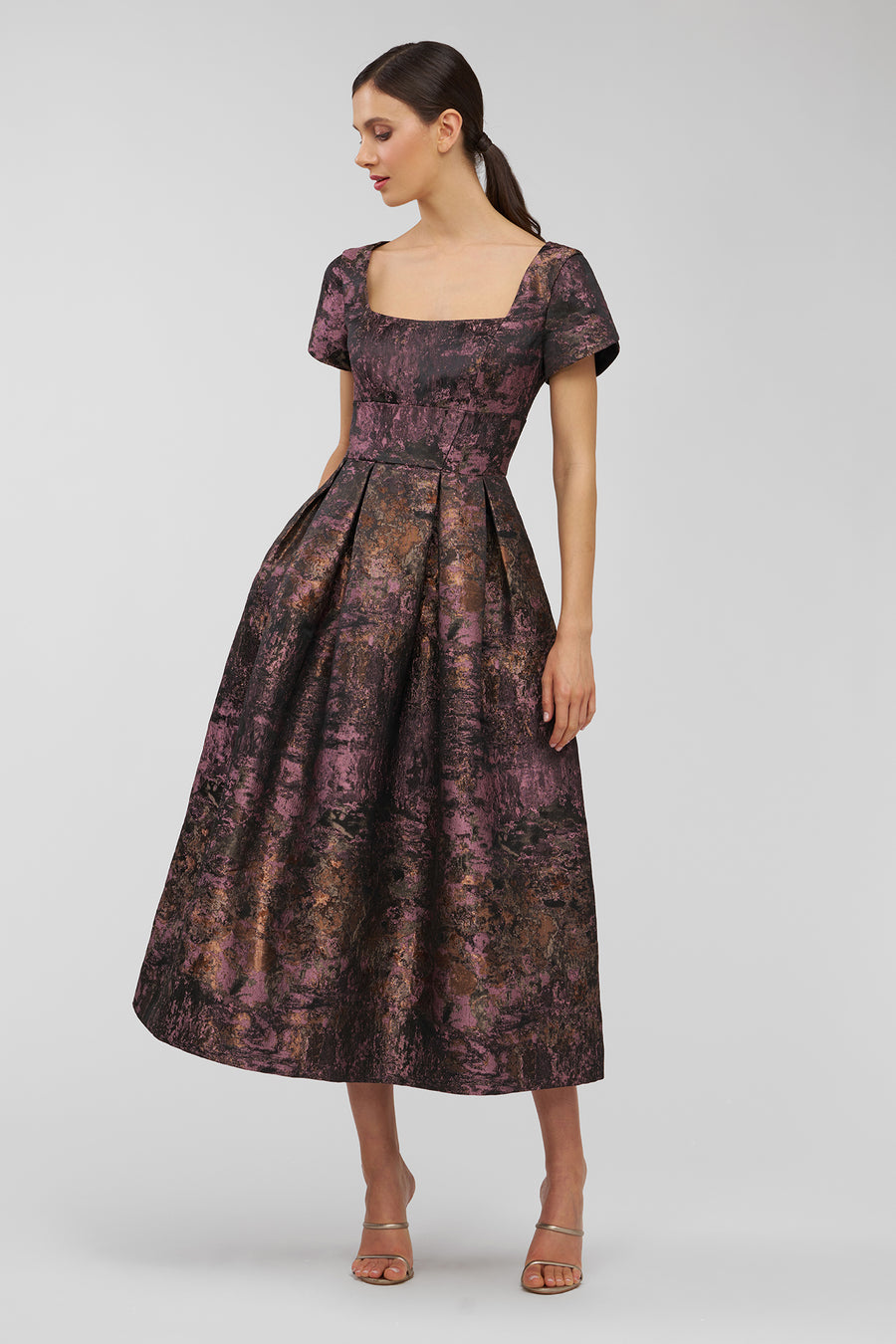 Woman wearing a patterned dress on a plain background