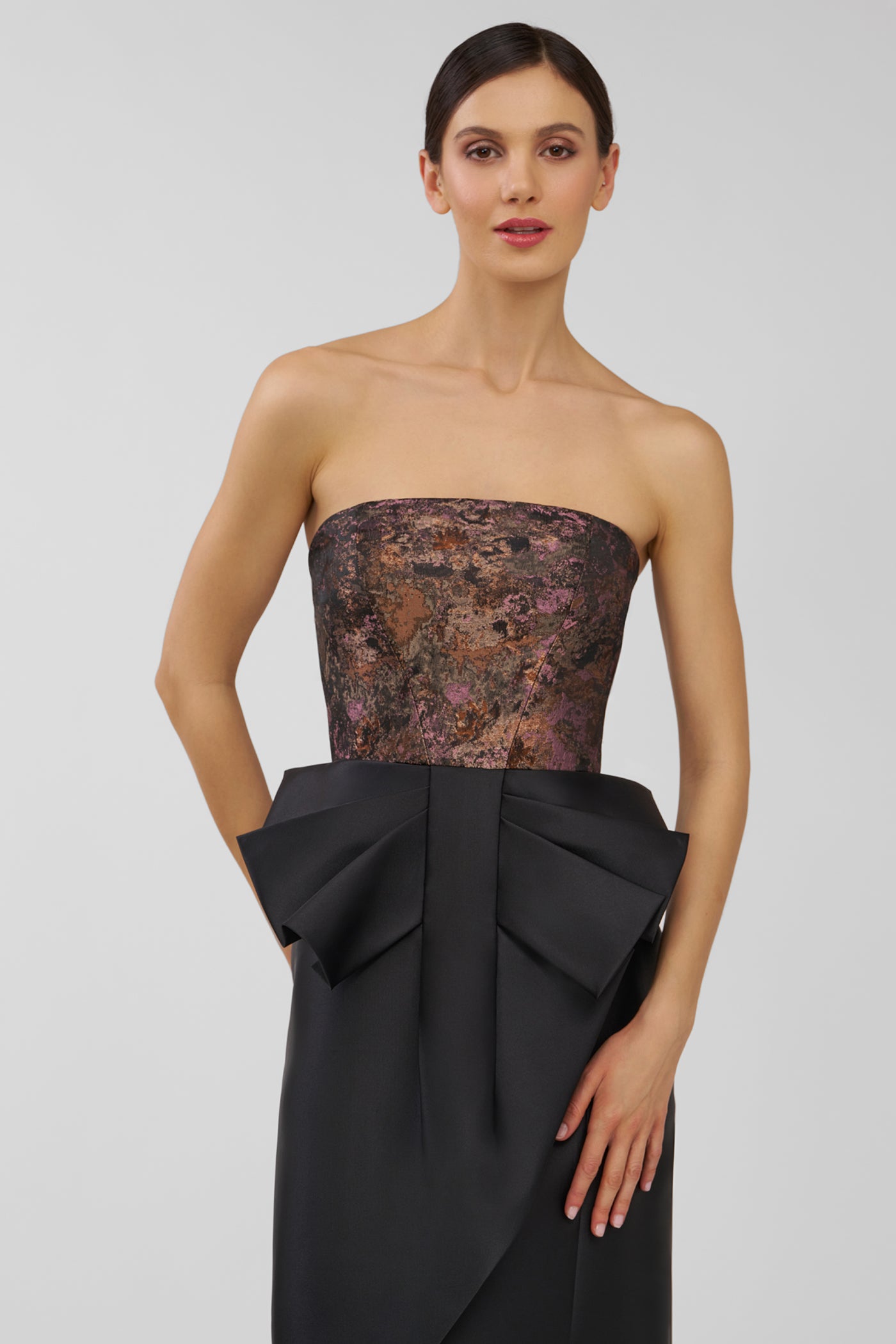 Woman wearing a strapless dress with a textured bodice and black skirt on a plain background