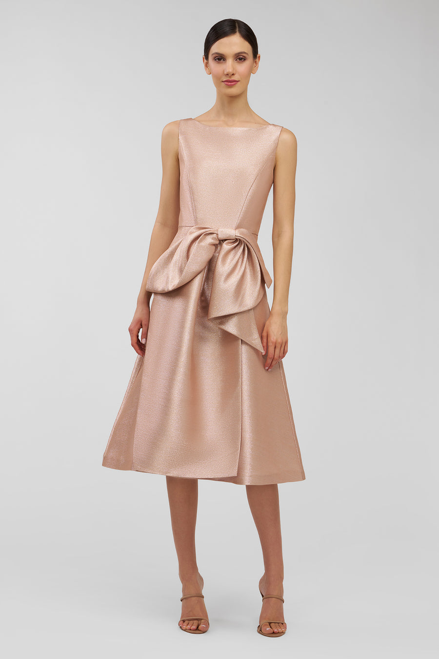Woman wearing a blush pink dress with a bow detail on a light gray background