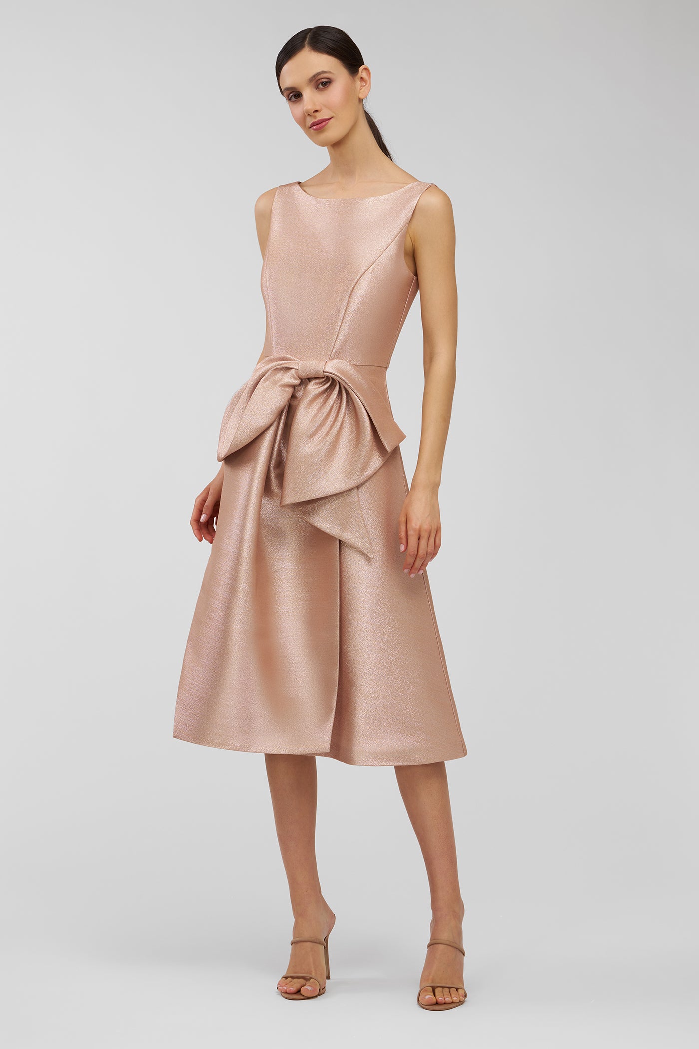 Woman wearing a pink dress with a bow detail on a white background