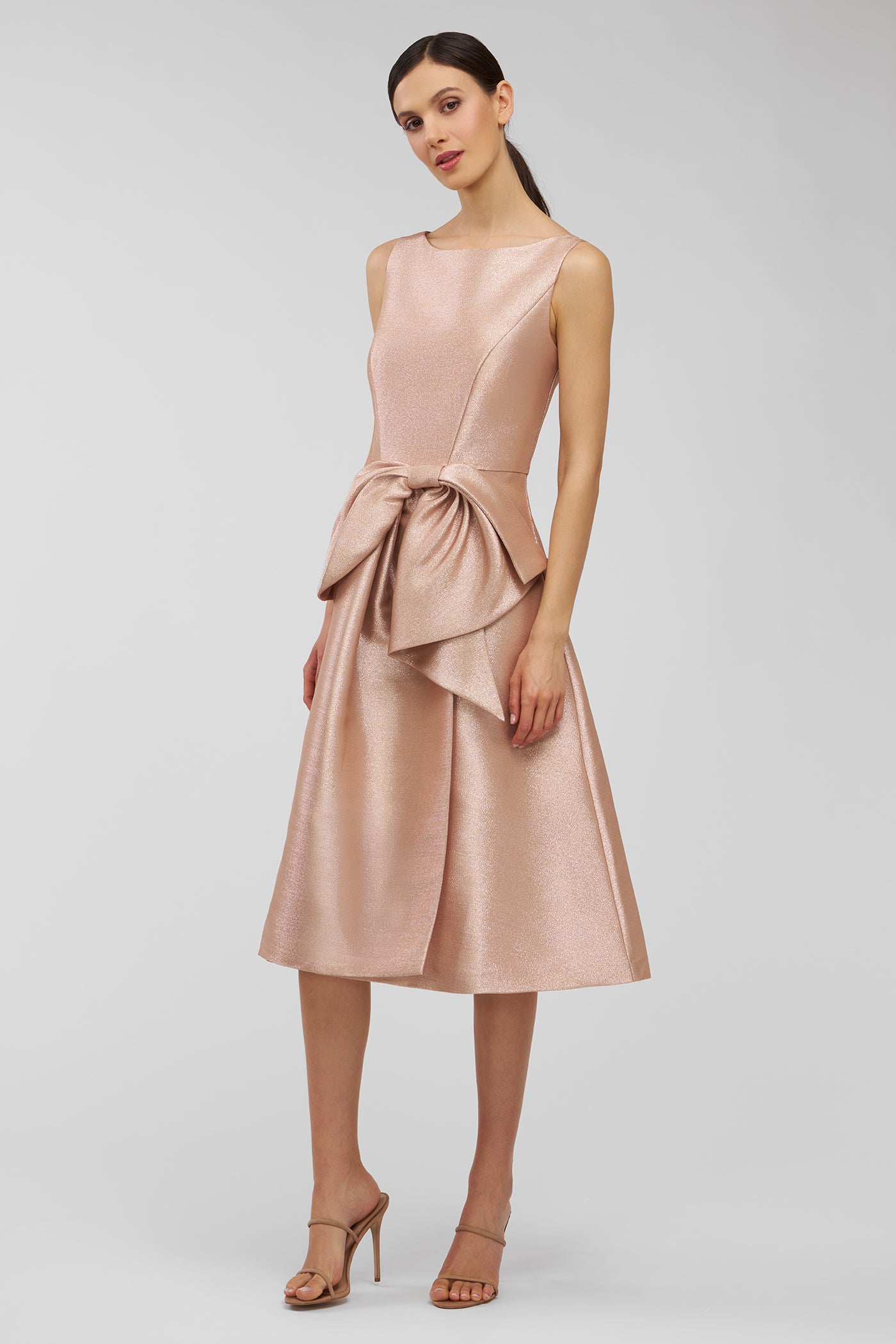 Woman wearing a pink dress with a bow detail on a white background