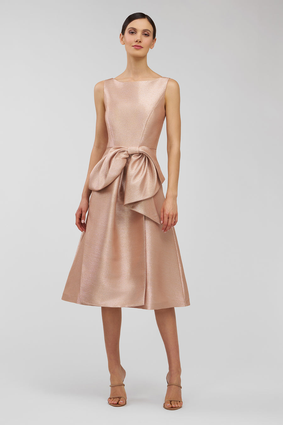 Woman wearing a rose gold dress with a bow detail on a white background