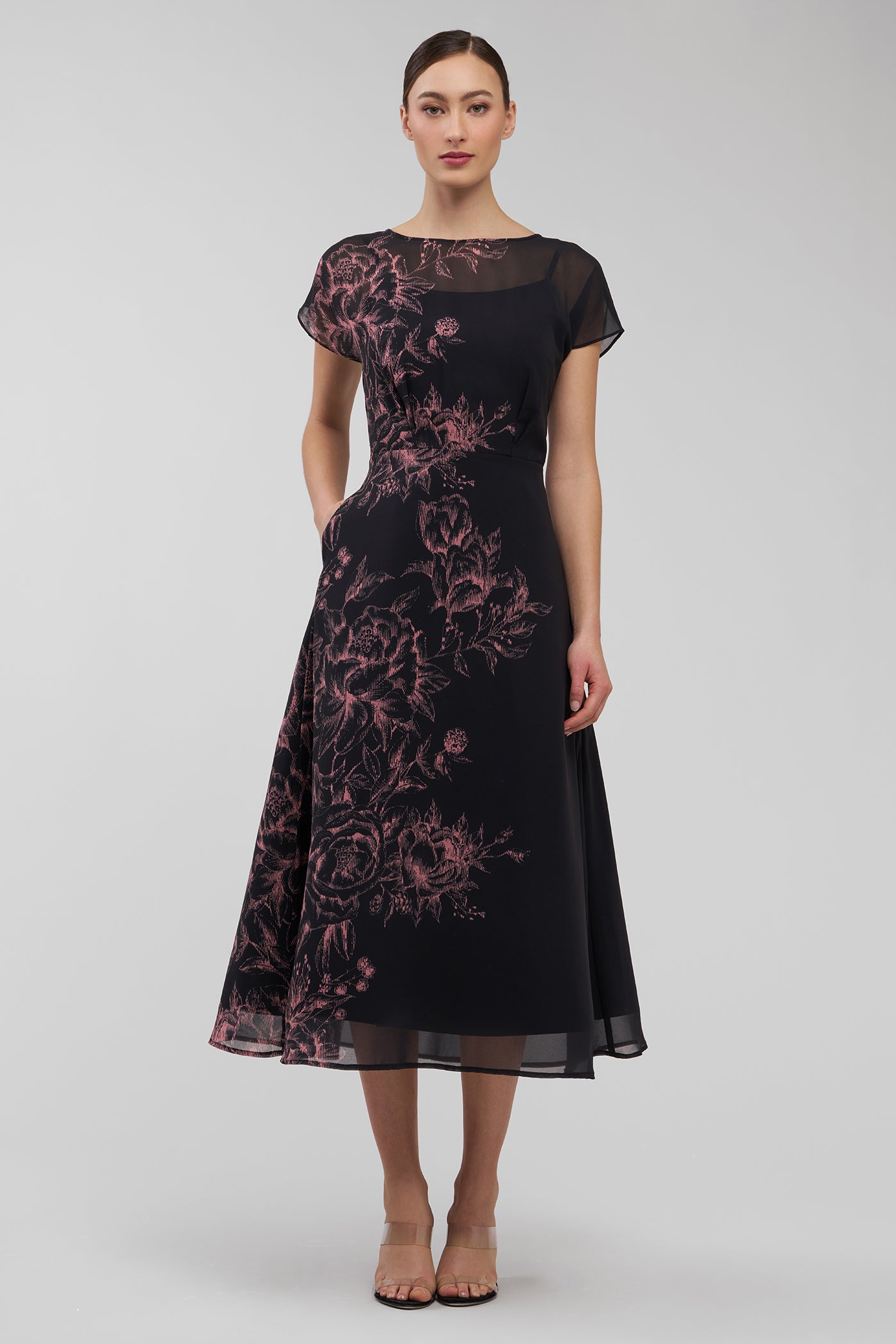 Woman wearing a black dress with pink floral patterns on a white background