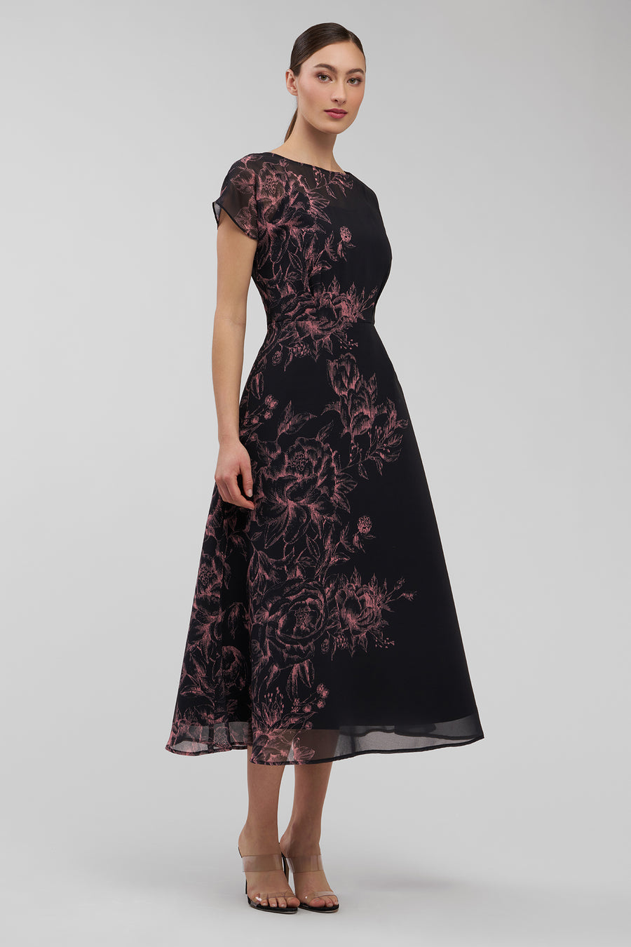Woman wearing a black dress with pink floral pattern on a white background