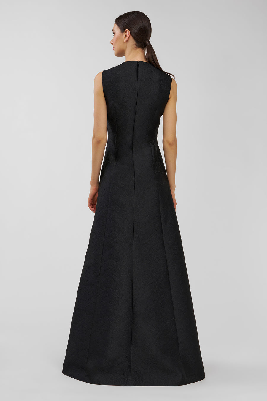 Woman wearing a black sleeveless gown on a light gray background