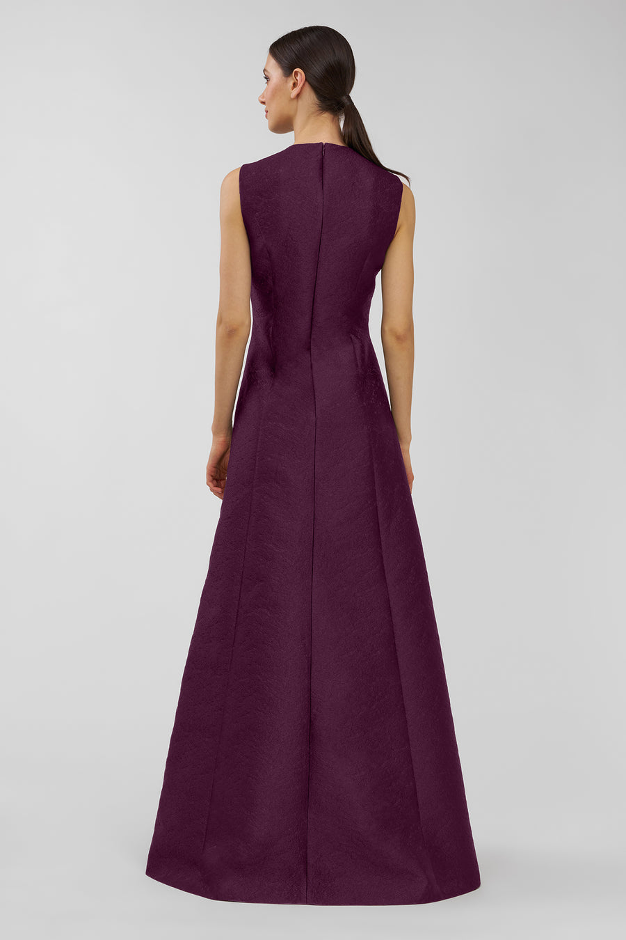 Woman wearing a long purple dress on a light gray background