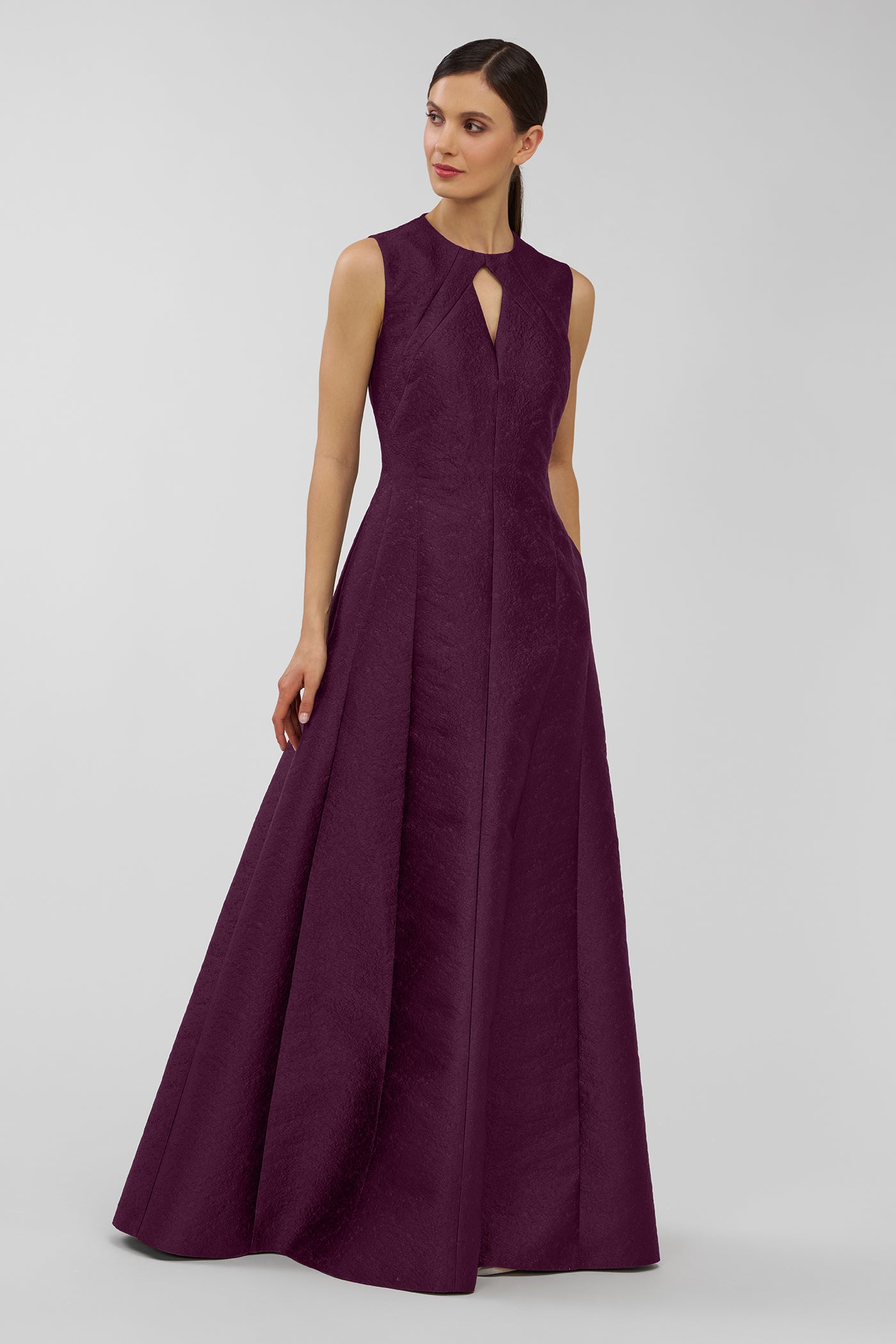 Woman wearing a long purple dress on a gray background