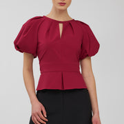 Woman wearing a red blouse with puffed sleeves on a white background