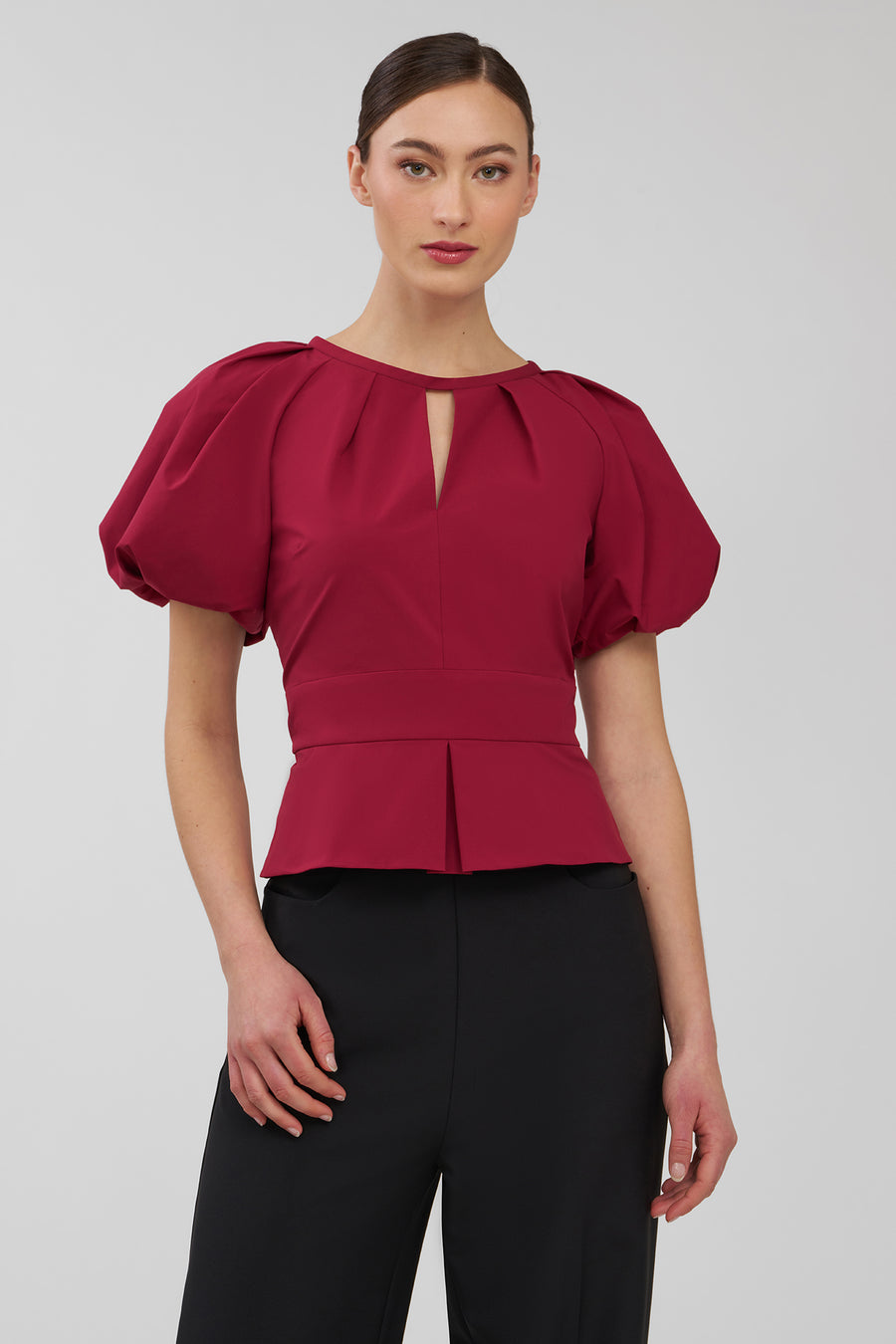 Woman wearing a red blouse with puffed sleeves on a white background
