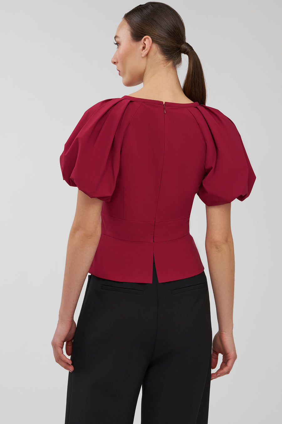 Woman wearing a red blouse with puff sleeves on a white background
