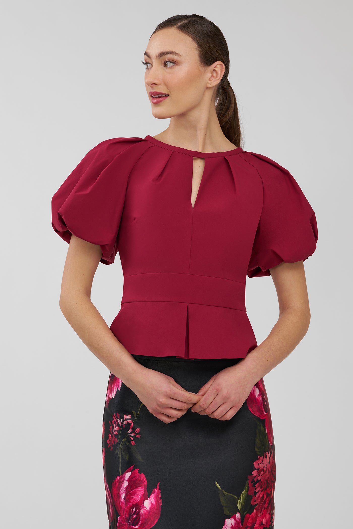 Woman wearing a red blouse with puff sleeves on a plain background