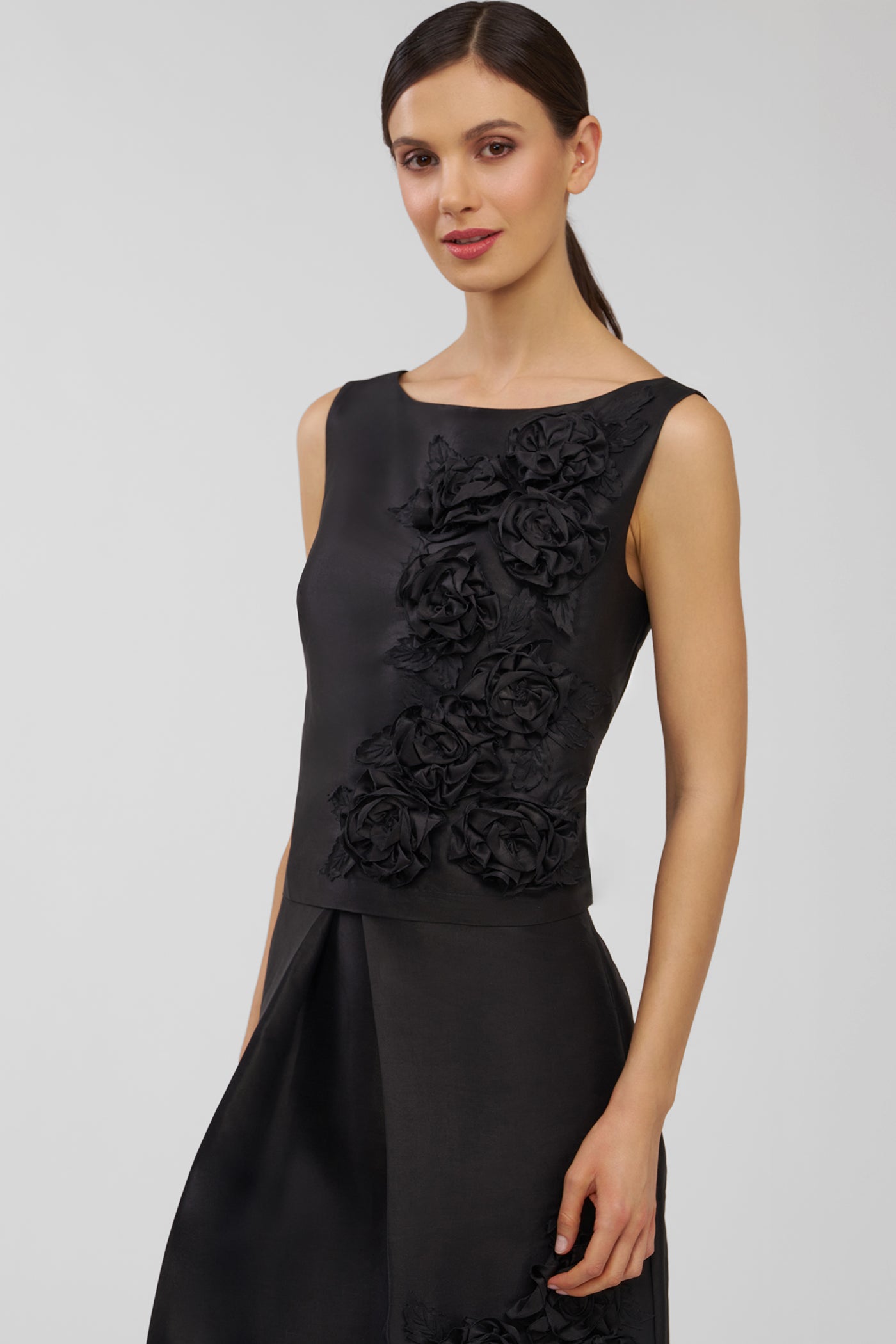 Woman wearing a black top with floral details on a gray background